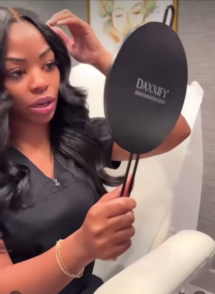 A client admiring her refreshed, radiant results in a hand mirror after a treatment