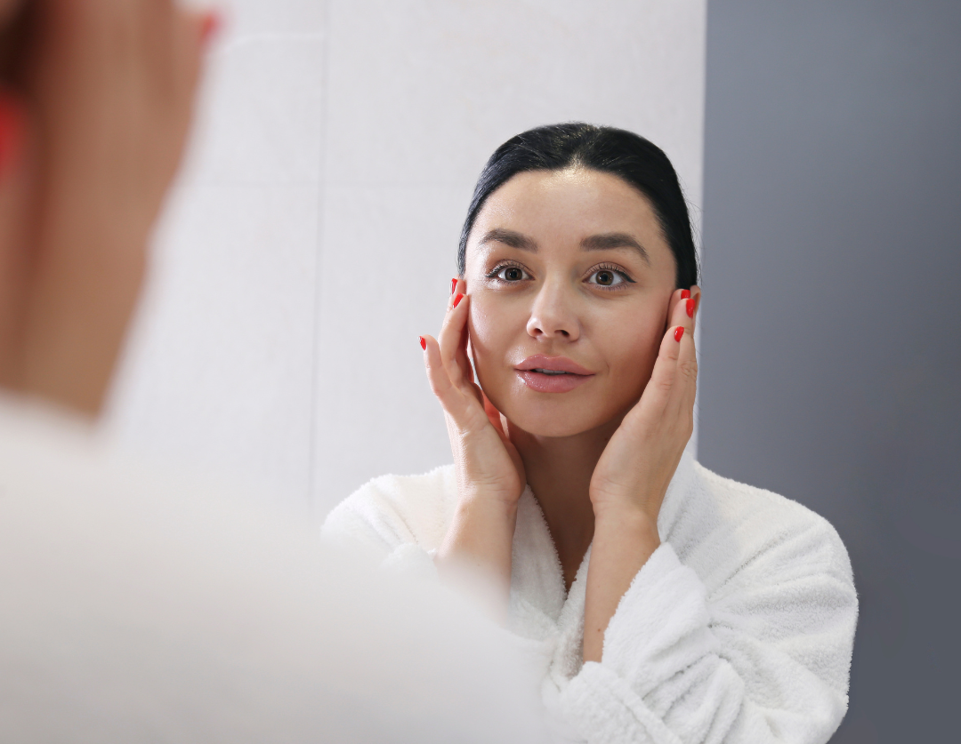 Woman admiring her smooth, radiant skin in the mirror after a chemical peel